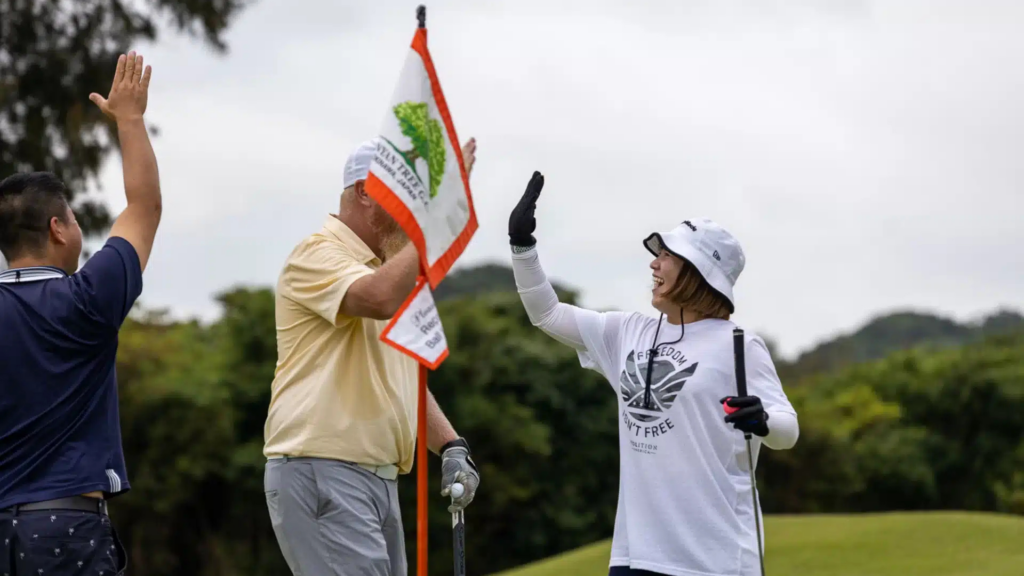Golfers high-five and celebrate on the golf course.